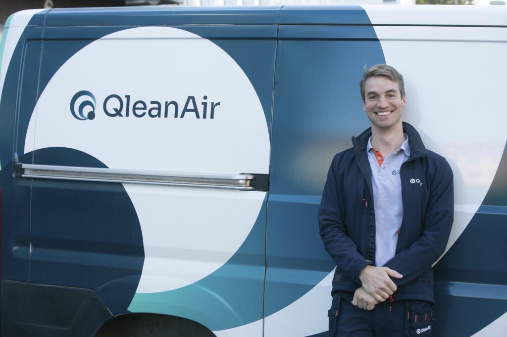 Two Qleanair service technicians, male and female, standing outside the QleanAir Service Car 