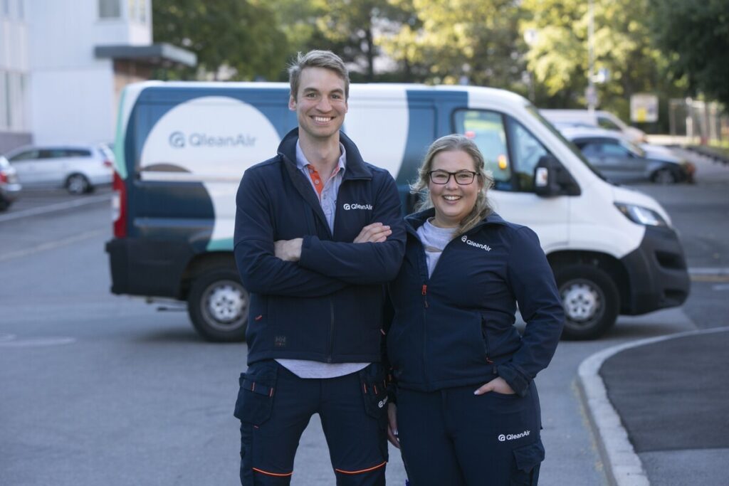 Two Qleanair service technicians, male and female, standing outside the QleanAir Service Car 